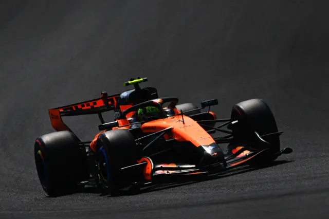 Болід McLaren на трасі під час Гран-прі Японії, водій у шоломі, яскраве освітлення