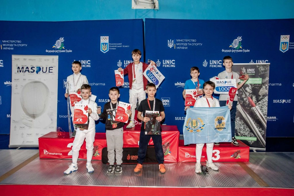 Юні фехтувальники з медалями та прапорами на п'єдесталі пошани під час змагань «Biopharma Cup» у Білій Церкві