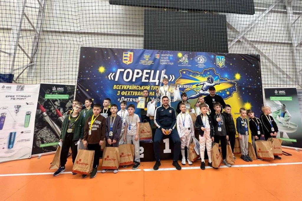 Юні учасники змагань з фехтування на шпагах на сцені з нагородами та подарунками в Ужгороді