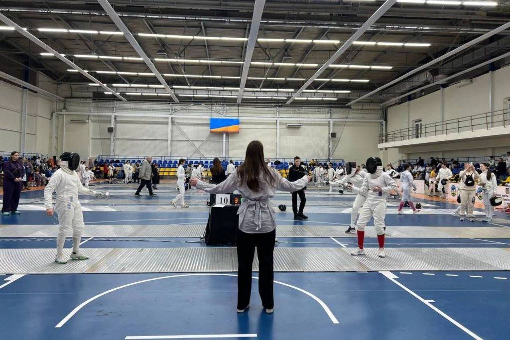 Юні фехтувальники змагаються на турнірі в Ужгороді, суддя спостерігає за поєдинком на доріжці