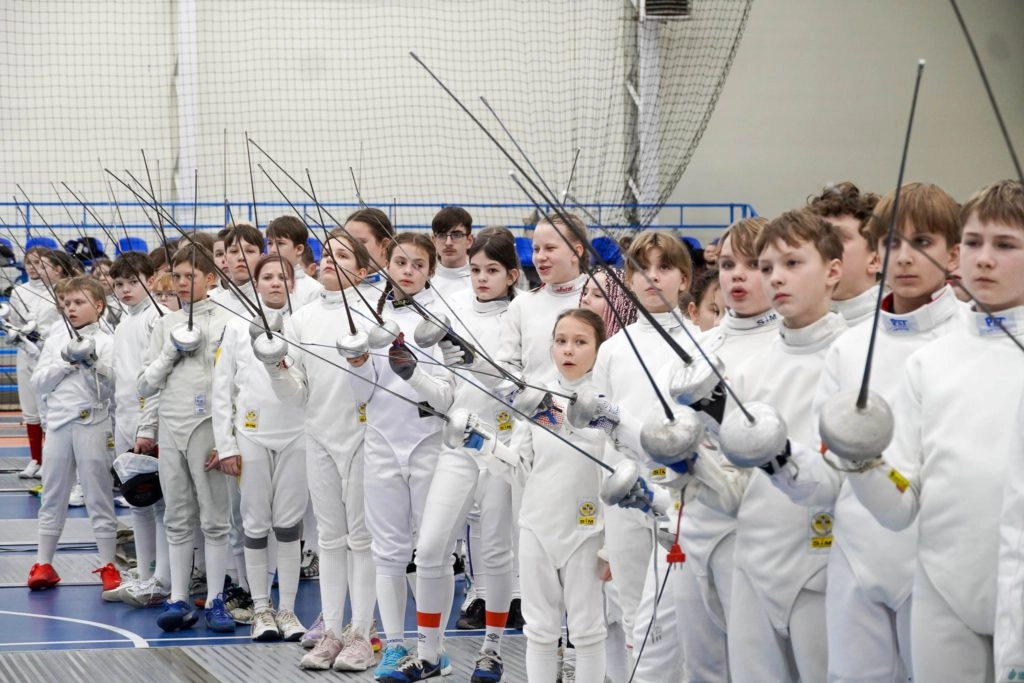 Юні фехтувальники в білих костюмах з шпагою в руках на турнірі в Ужгороді, готові до змагань