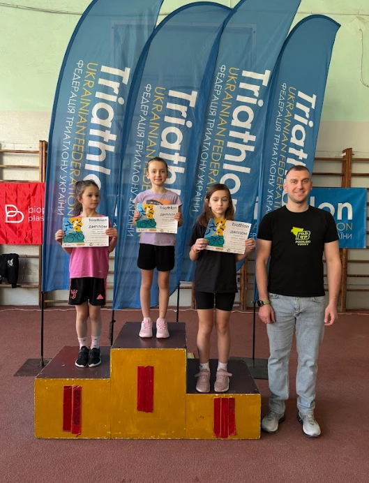 Три юні спортсменки на п'єдесталі з нагородами після змагань з акватлону в Хмельницькому