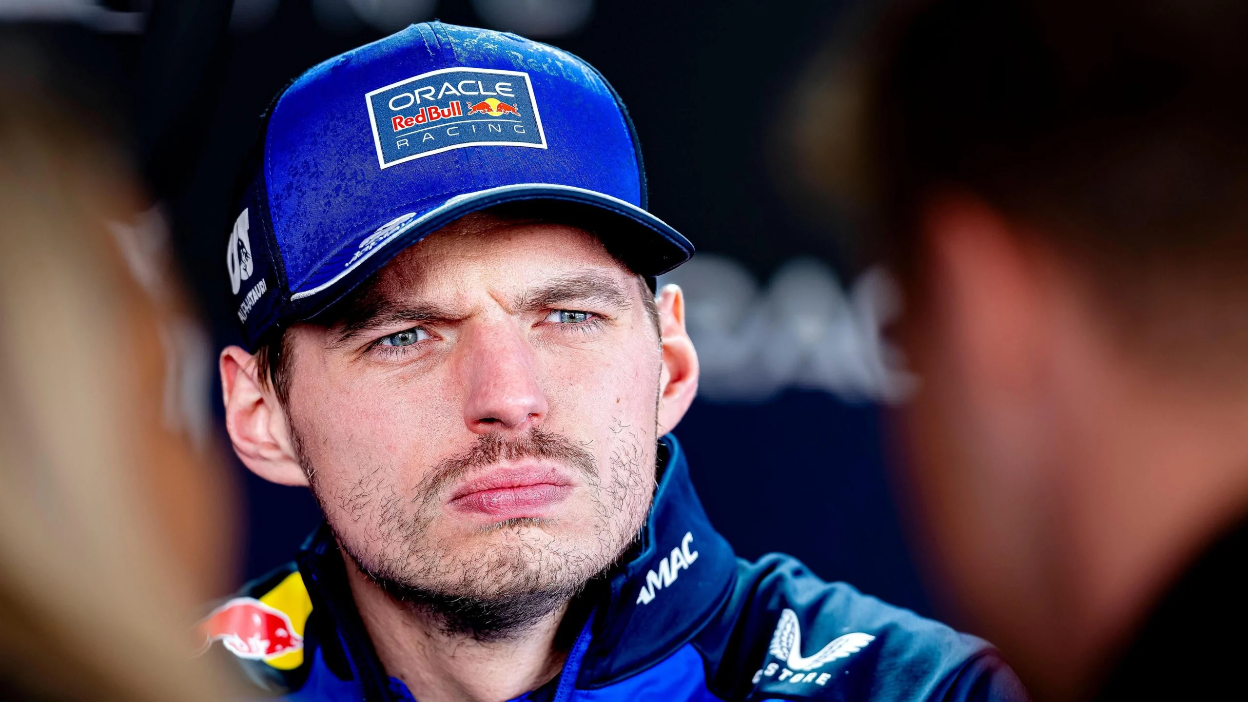 На зображенні гонщик у синій кепці з логотипом Red Bull Racing, зосереджений перед гонкою