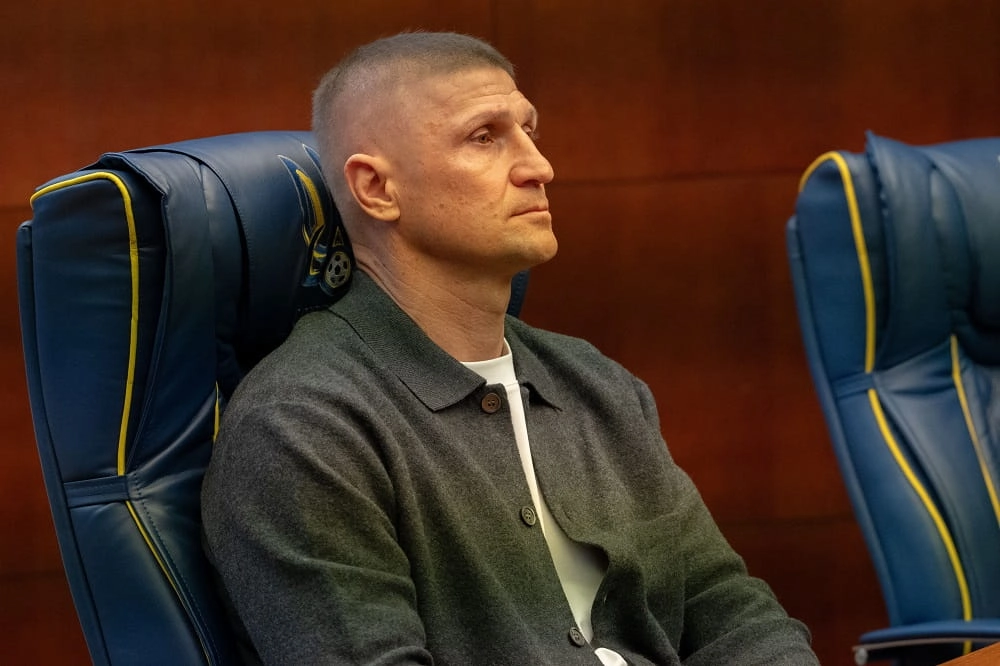 Тренер сидить на синьому кріслі під час наради в Будинку футболу в Києві