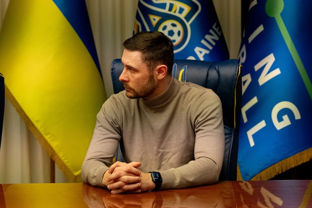 Тренер на нараді в Будинку футболу, на задньому плані прапори України та футбольної асоціації
