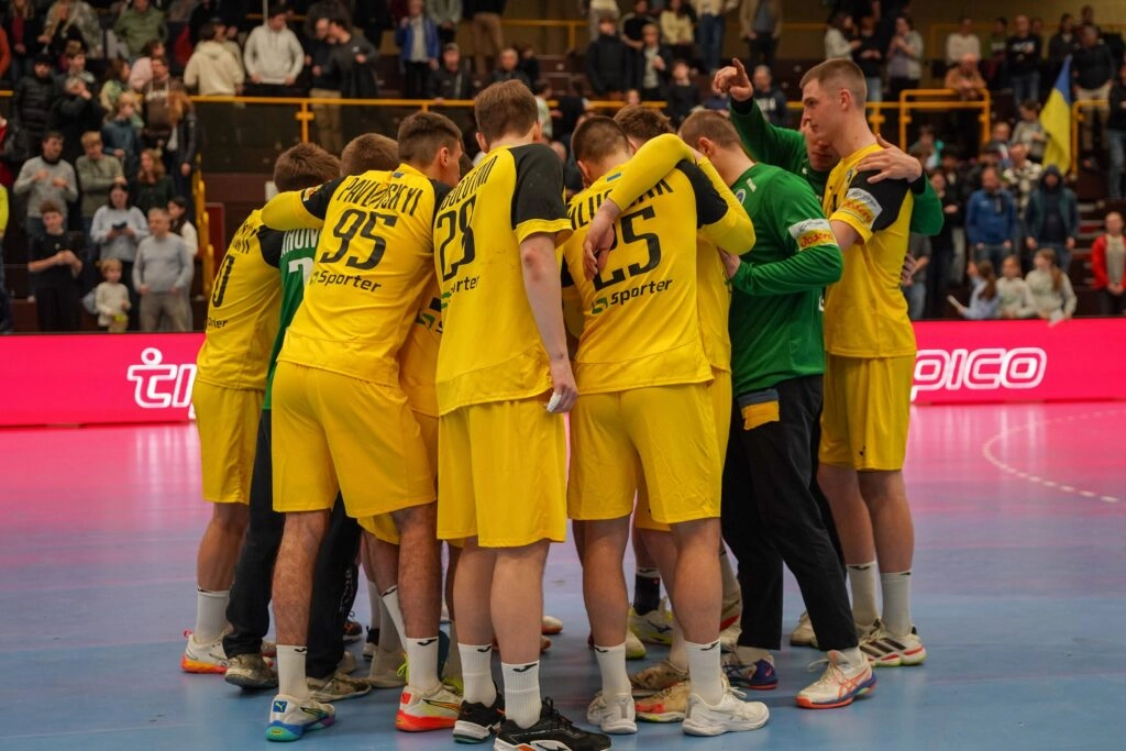 Українська чоловіча збірна з гандболу в жовтій формі обговорює стратегію перед матчем зі Словаччиною