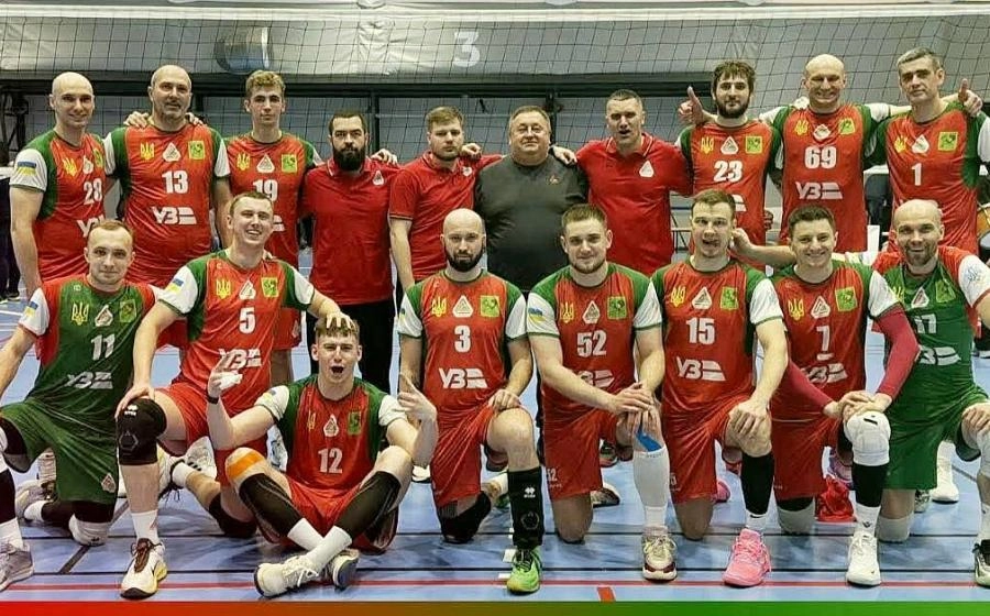 Волейбольна команда у червоно-зеленій формі позує на майданчику після матчу