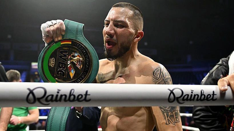 Боксер тримає чемпіонський пояс WBC на рингу після перемоги в бою, виглядає задоволеним