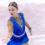 Фігуристка в синій сукні виконує елемент на льоду під час змагань в Одесі, демонструючи майстерність