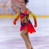 Юна фігуристка в яскравому костюмі виконує елемент на льоду під час змагань в Одесі