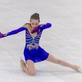 Юна фігуристка в яскравому костюмі виконує елемент на льоду під час змагань в Одесі