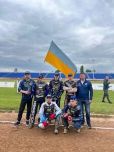Група людей у спортивній формі з українським прапором на мотоспортивному заході