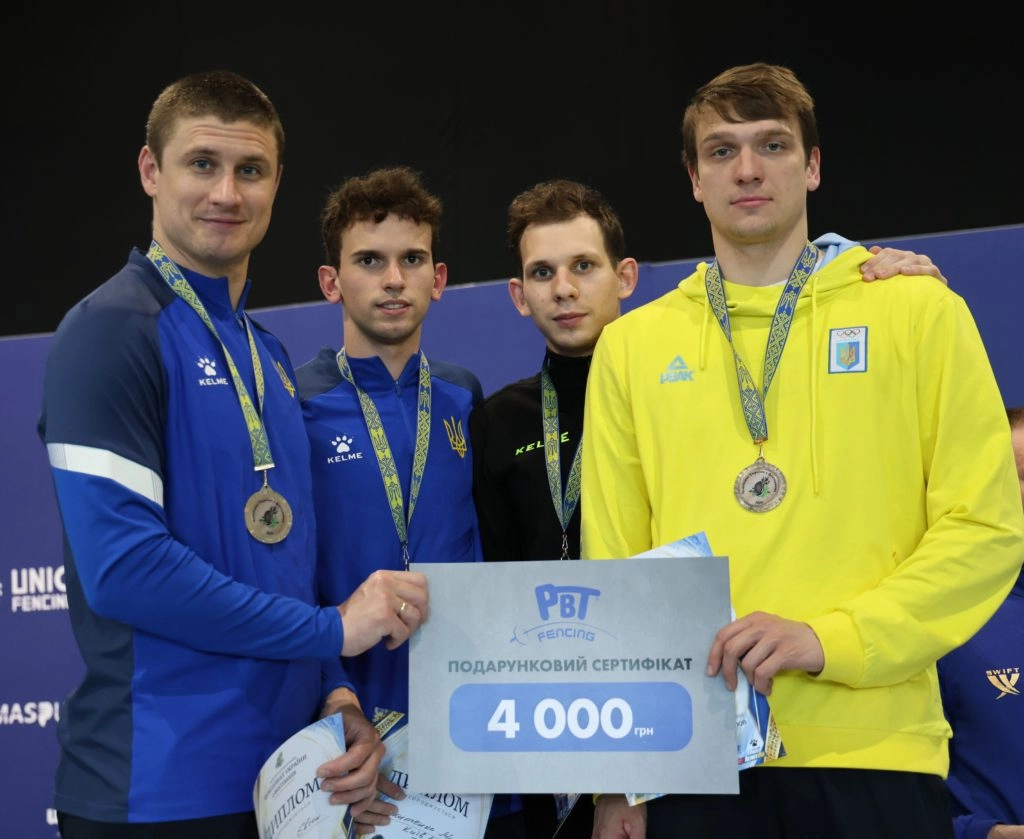 Шпажисти Харкова святкують перемогу на чемпіонаті України-2026 у Києві, тримаючи сертифікат 4000 грн